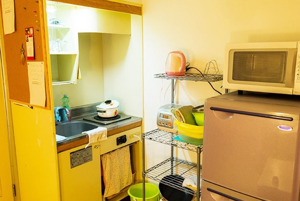 Kitchen with dishes, cutlery, cups and kitchenware, refrigerator, microwave, toaster, rice cooker
